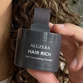 Woman with curly hair holding HAIR RICH hair concealer by Aluzera